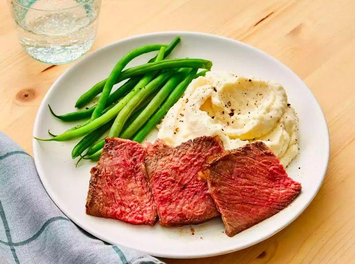 Rib-eye roast served alongside creamy mashed potatoes and tender green beans