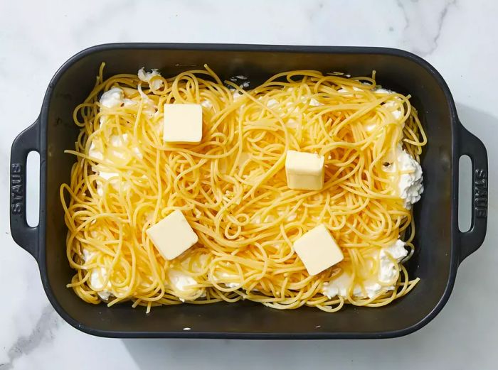 The mixture is topped with the remaining spaghetti and butter slices.