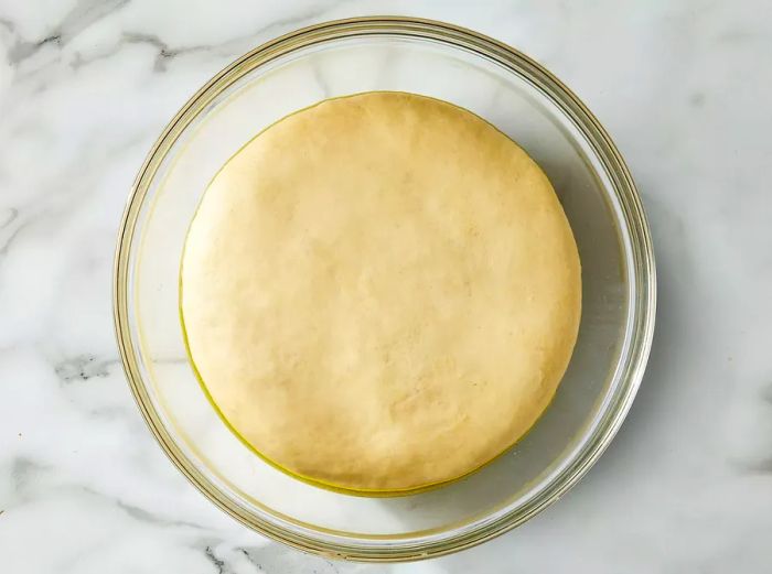 A top-down view of smooth dough in a glass bowl