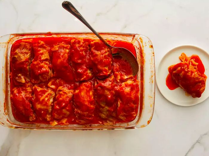 An overhead view of a baking dish filled with tomato sauce-covered stuffed cabbage rolls after they've been cooked.