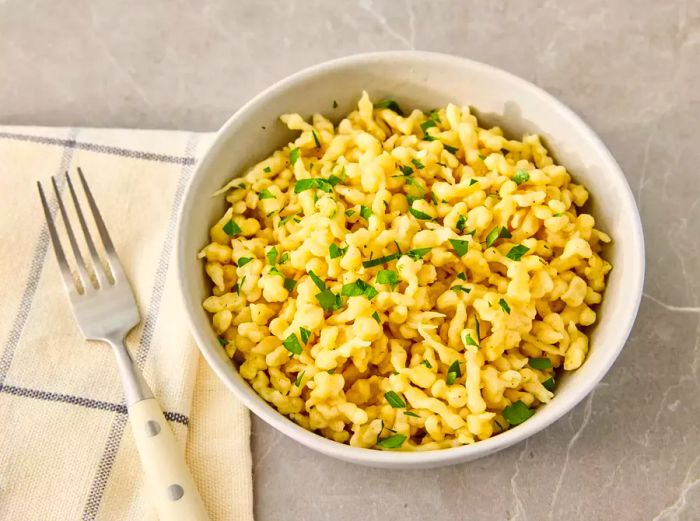 A bowl of German spaetzle dumplings, garnished with chopped parsley