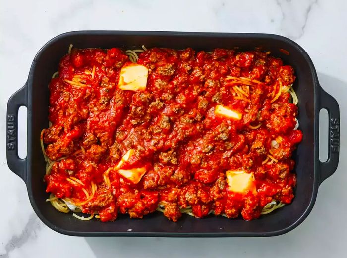 Ground beef mixture poured over spaghetti and evenly spread.