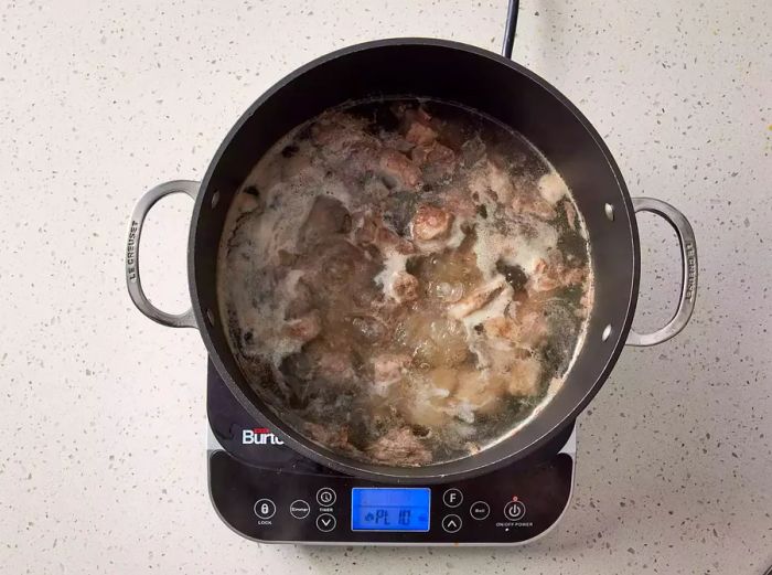 A pot with pork spareribs boiling in water.