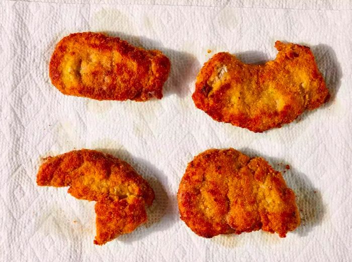 Golden-brown cutlets draining on paper towels.