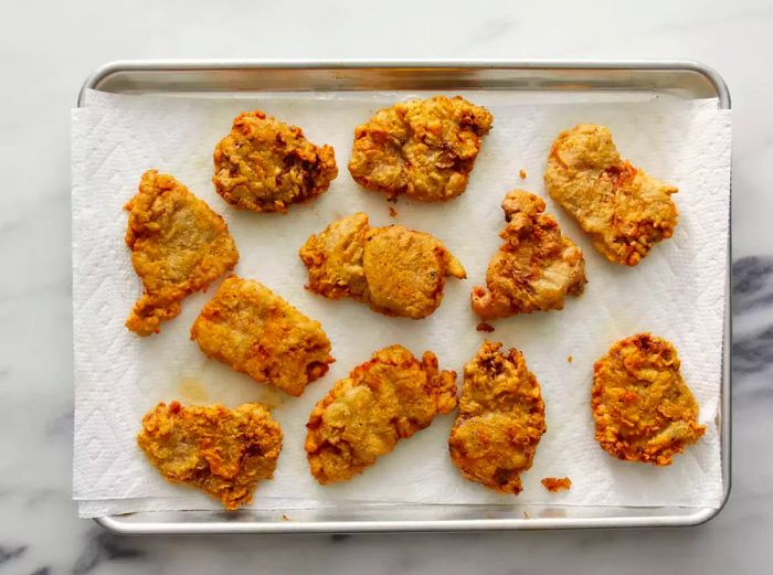 An overhead view of Fried Venison Backstrap resting on a baking sheet lined with paper towels