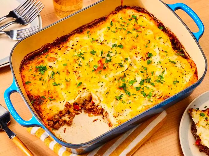 A golden cheese-topped cottage pie in a blue baking dish, freshly baked.