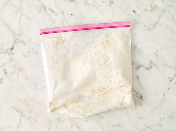 An overhead view of a flour mixture in a resealable plastic bag.