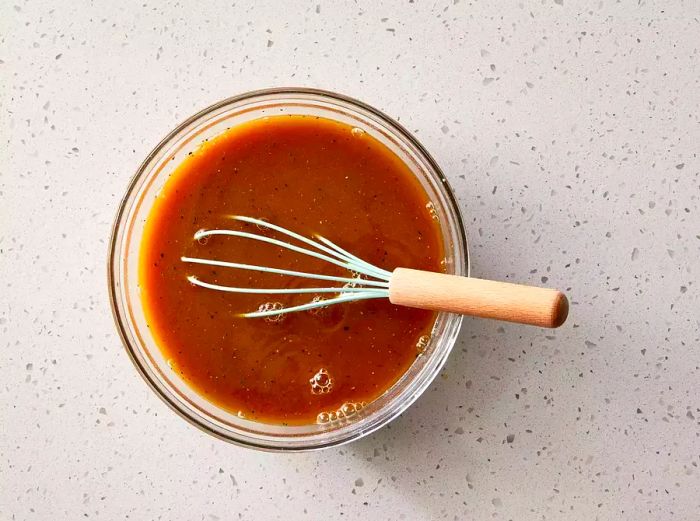 A bowl of sweet and sour sauce being whisked.