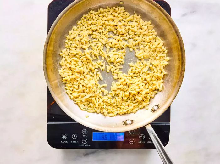 A large skillet with German spaetzle cooking in melted butter