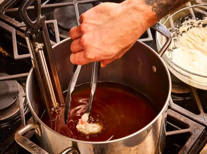 A shrimp coated in batter frying in hot oil in a large pot