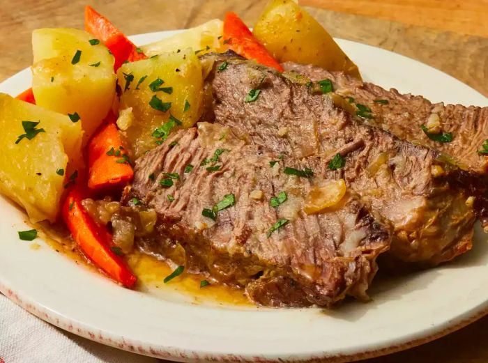 Aerial view of a plate filled with tender beef pot roast, accompanied by carrots and potatoes.