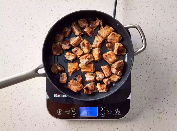 A pan with browned pieces of pork spareribs.