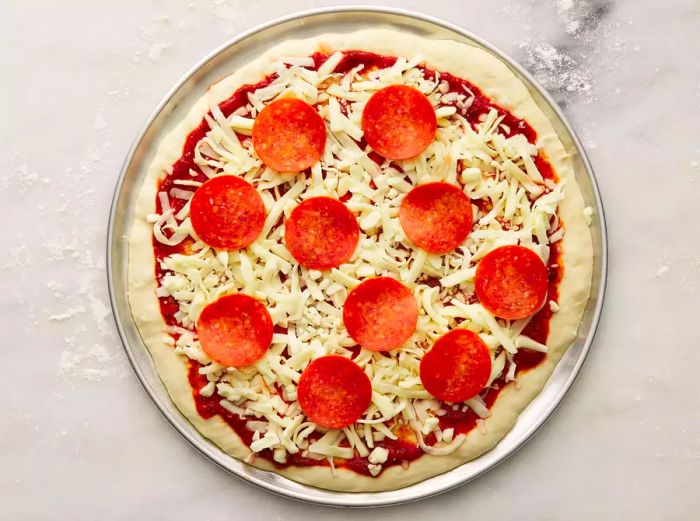 An aerial shot of an unbaked pepperoni pizza on a pizza pan.