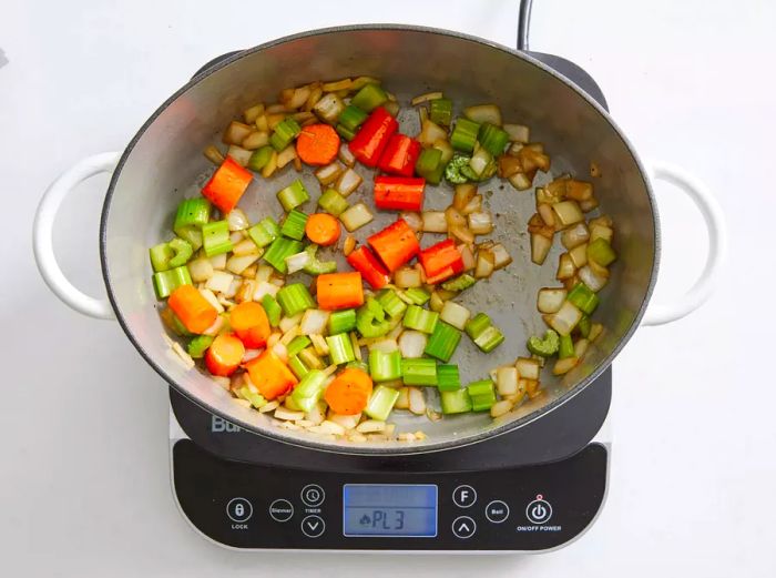 A large pot with diced carrots, onions, and celery