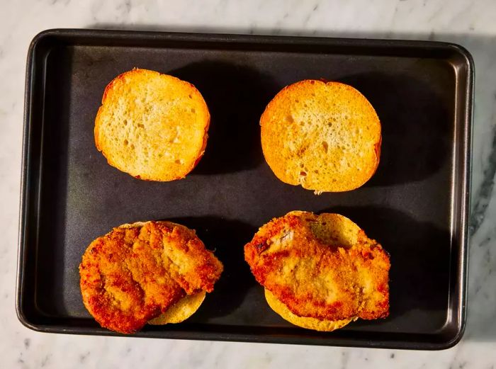 Fried cutlets placed on the bottom half of the buns.