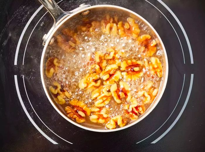 A small pot with walnuts simmering in a sweet sugar-water mixture