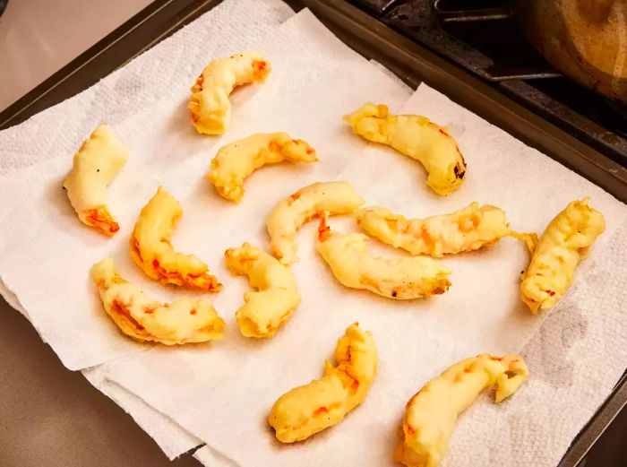 A baking sheet lined with paper towels holding crispy fried shrimp