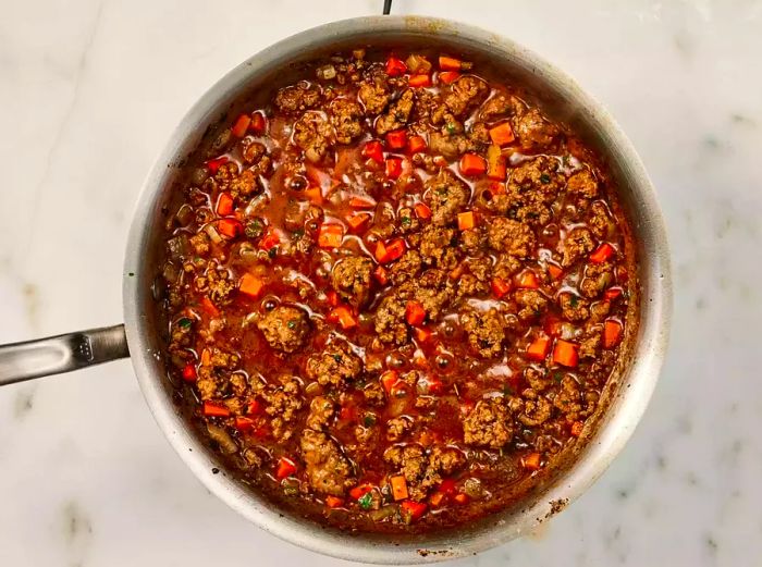 Beef mixture simmering in a skillet with vegetables and gravy.