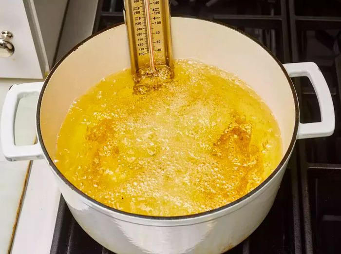 A large pot filled with cubed chicken breasts frying in hot oil, sizzling away.