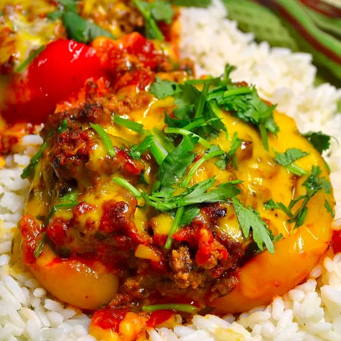 Close-up shot of stuffed Mexican peppers served on white rice, garnished with fresh herbs.