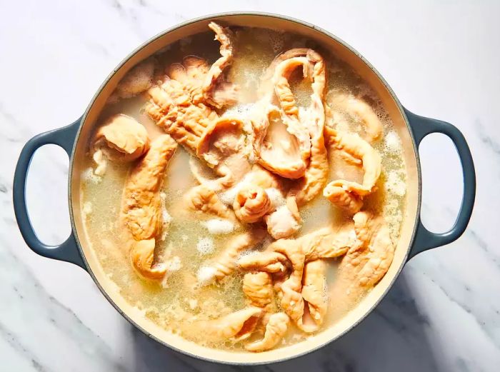 A large pot filled with chitterlings simmering in water.