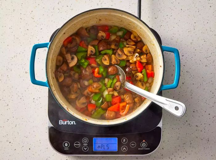 Mushrooms, red, and green peppers sautéing in the Dutch oven.