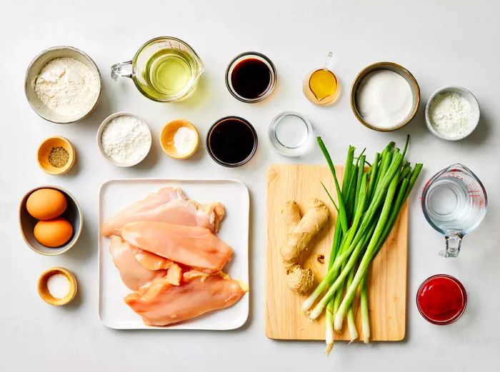 Lay out the chicken, ginger, green onions, and various sauces on a countertop.