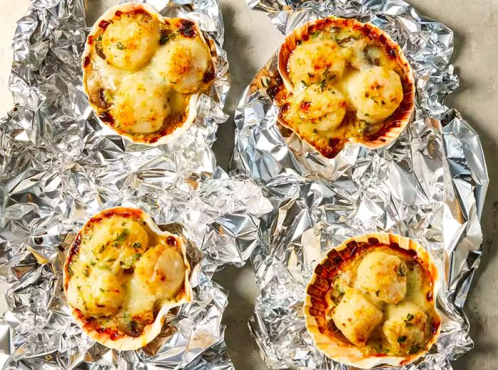 Four servings of Coquilles Saint-Jacques, topped with golden, melted cheese