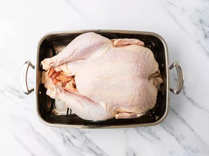 Raw turkey placed in a roasting pan.