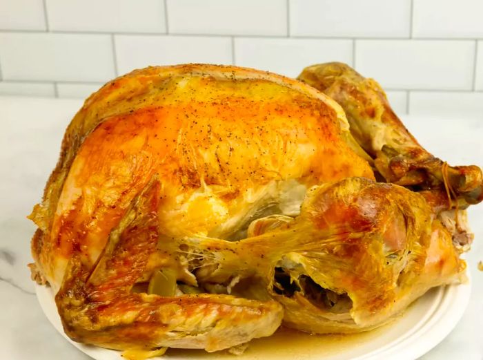 A beautifully roasted turkey resting on a white plate.