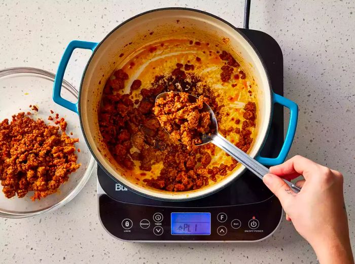 Chorizo being removed from the Dutch oven.