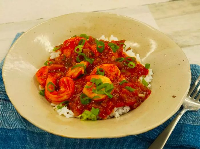 A serving of Louisiana shrimp Creole, beautifully plated over white rice in a beige bowl.