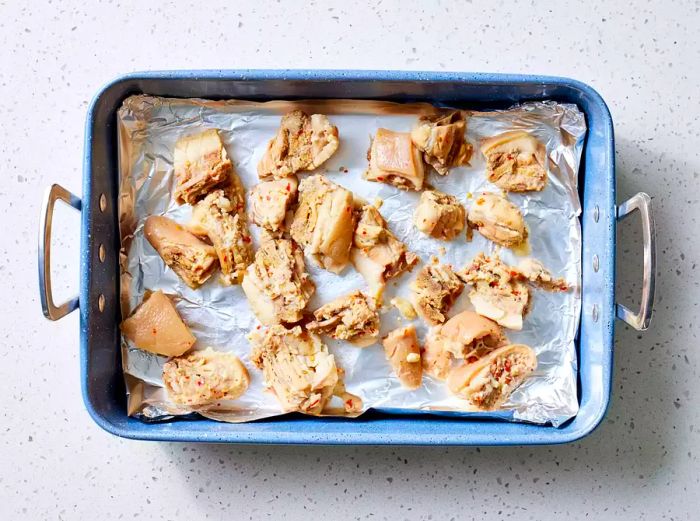 A roasting pan lined with foil and filled with boiled pig tails