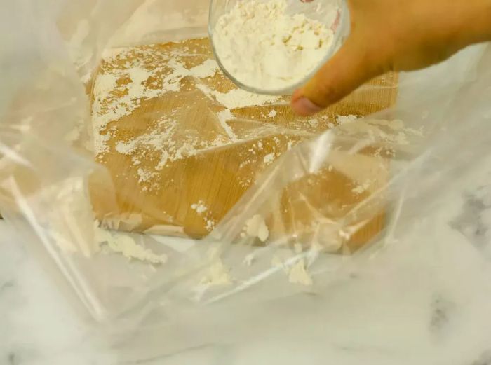 Flour being evenly spread across the bottom of the turkey bag.