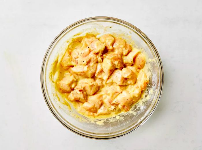 Marinated chicken chunks resting in a bowl, ready for the next step in cooking.