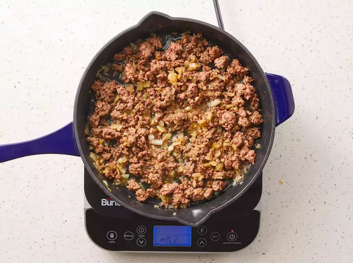 Ground beef and onions cooking together in a skillet until golden and tender.