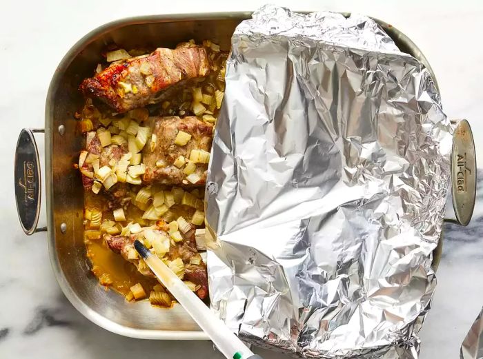 Basting the neck bones every half hour to ensure even cooking and flavor.