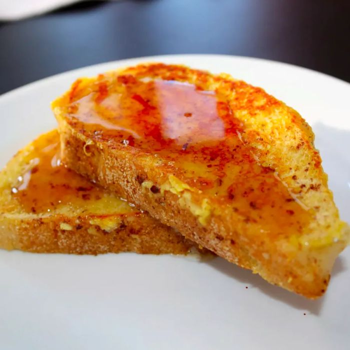 Close-up shot of Eggnog French Toast drizzled with syrup on a white plate