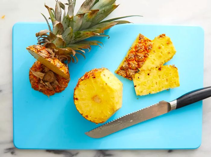 Pineapple being sliced into thick rings.