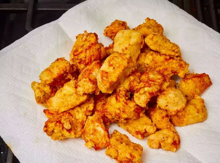 Crispy fried chicken pieces resting on a paper towel, absorbing excess oil.