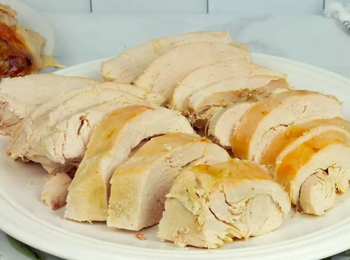 A close-up of sliced turkey arranged on a white platter.