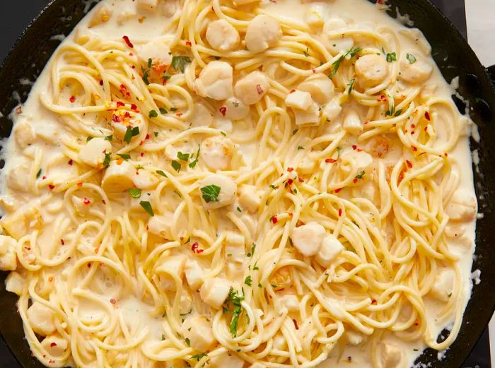 Aerial view of scallop pasta cooking together in a skillet.