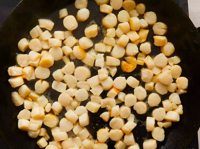 Aerial view of scallops cooking in a skillet.