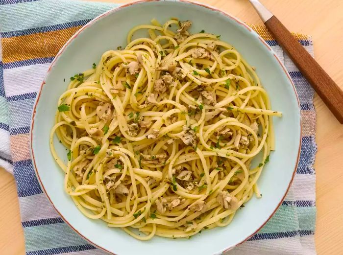 A generous serving of linguine topped with clam sauce and garnished with fresh chopped parsley