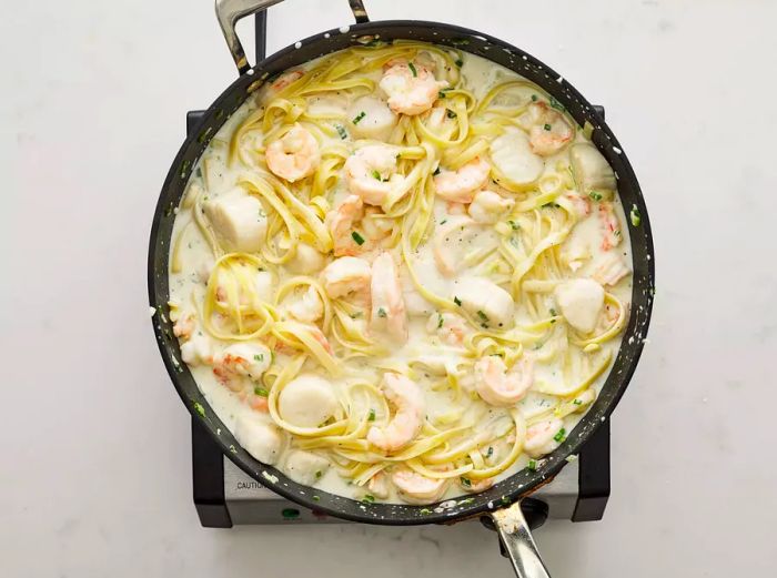 The fettuccine noodles have been added to the skillet and tossed until fully coated in the sauce.