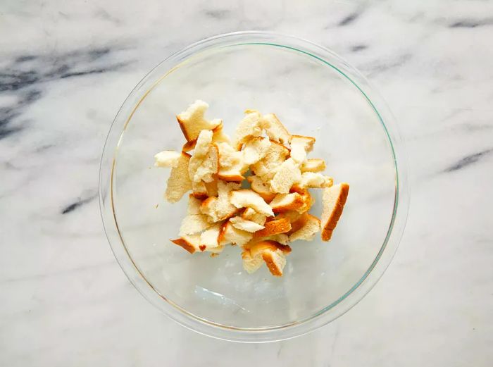 A top-down view of torn bread pieces resting in a bowl.