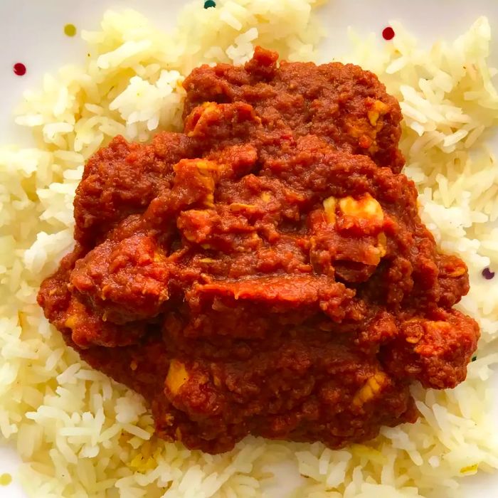 A close-up shot of Indian Tomato Chicken served over a bed of white rice on a plate.