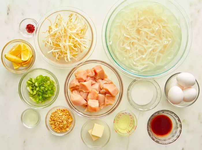 Bird's-eye view of pad Thai ingredients arranged in various glass bowls.