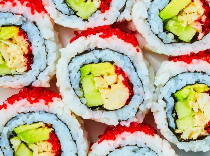 A sliced California roll, topped with tobiko, is displayed from above.