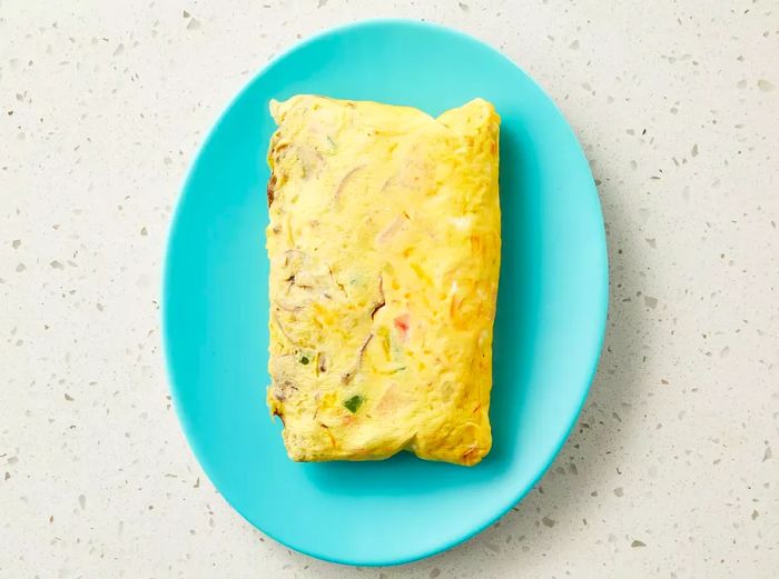 The omelet has been rolled out onto the plate, ready to serve.